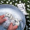 Close up of man washing US Dollars in pail outdoors