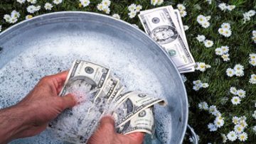 Close up of man washing US Dollars in pail outdoors