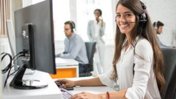 Friendly customer support service operator with headset working in call centre.